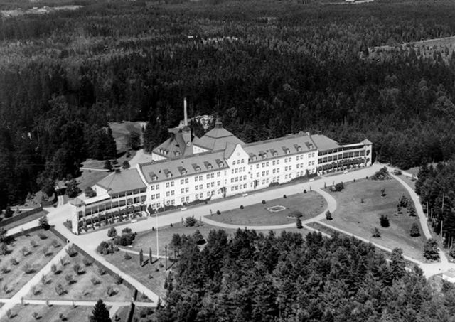 Svartvitt flygfoto över sanatoriet med flyglar, verandor och parken framför